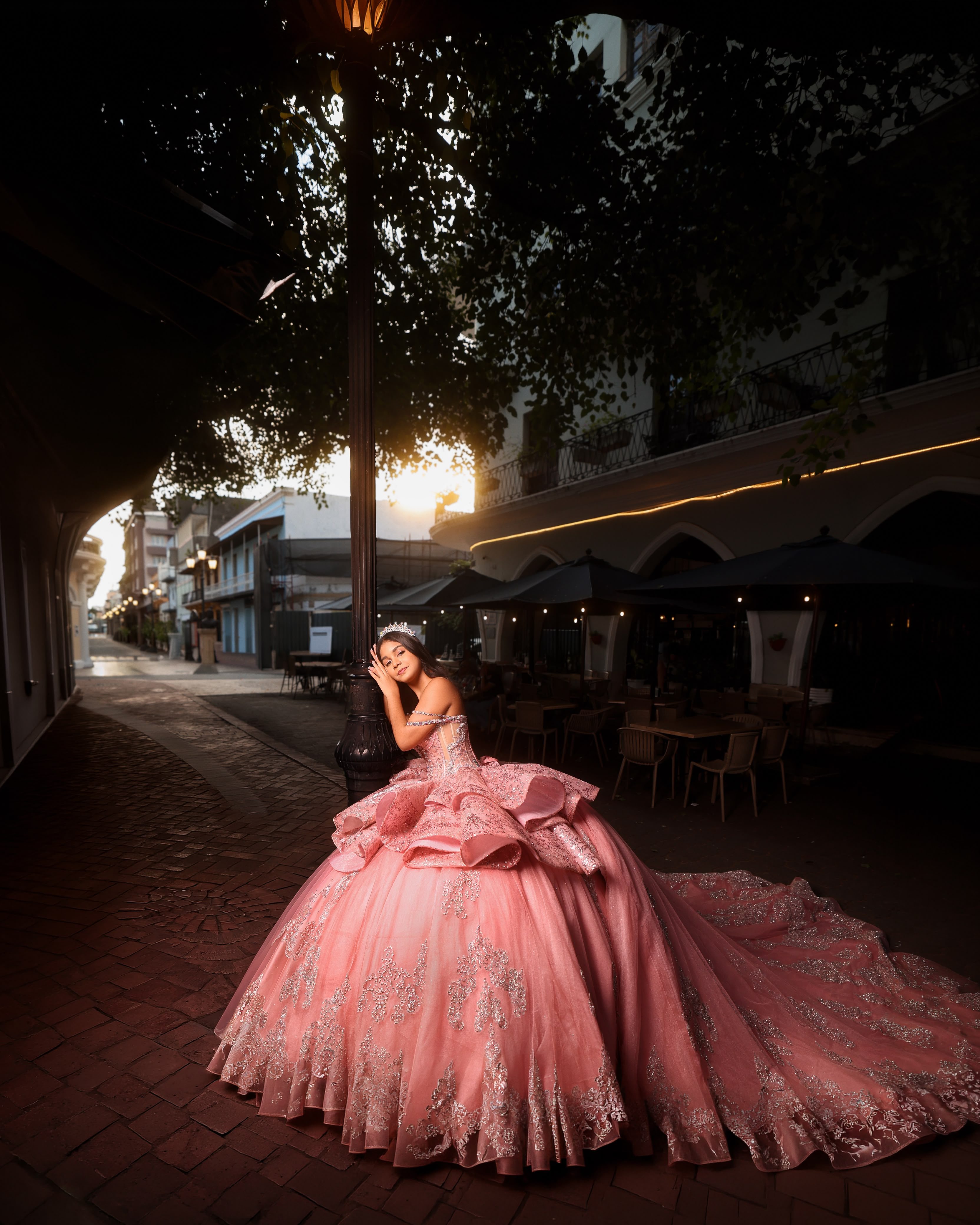 Quinceañera con vestido rosa de volantes en una calle colonial al atardecer