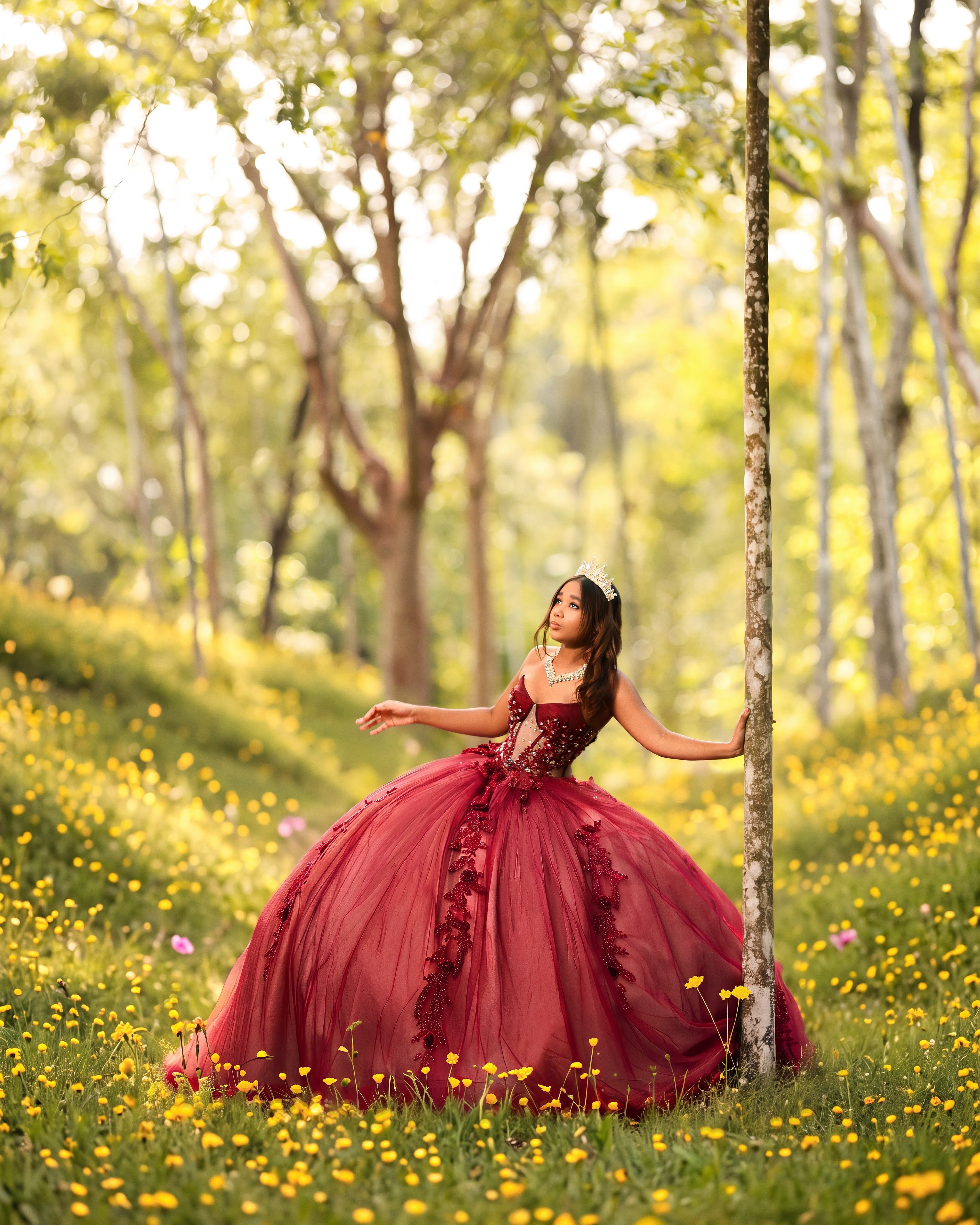 Quinceañera con vestido vino en un prado de flores amarillas