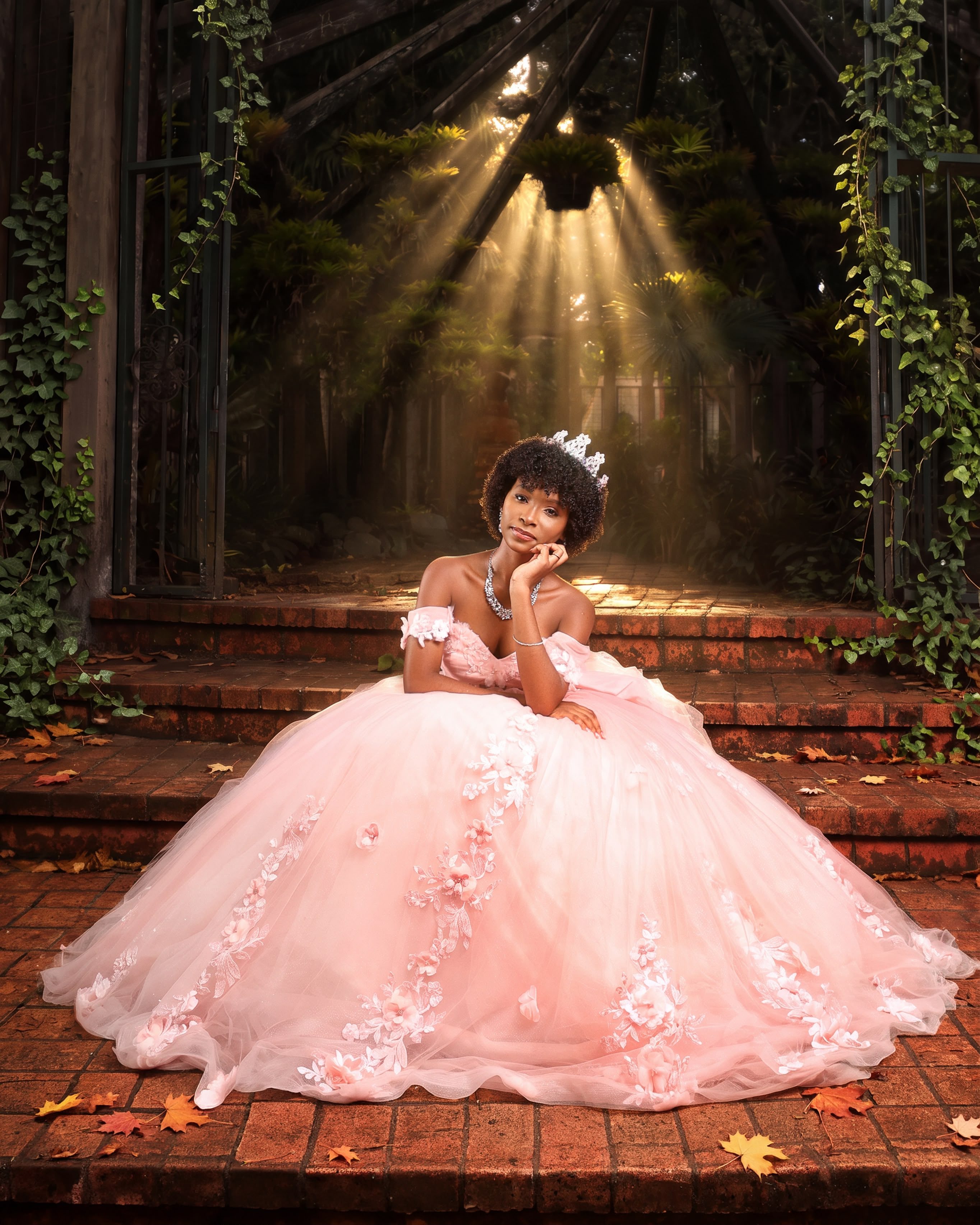 Quinceañera con vestido rosa de flores sentada en una escalinata bajo rayos de luz