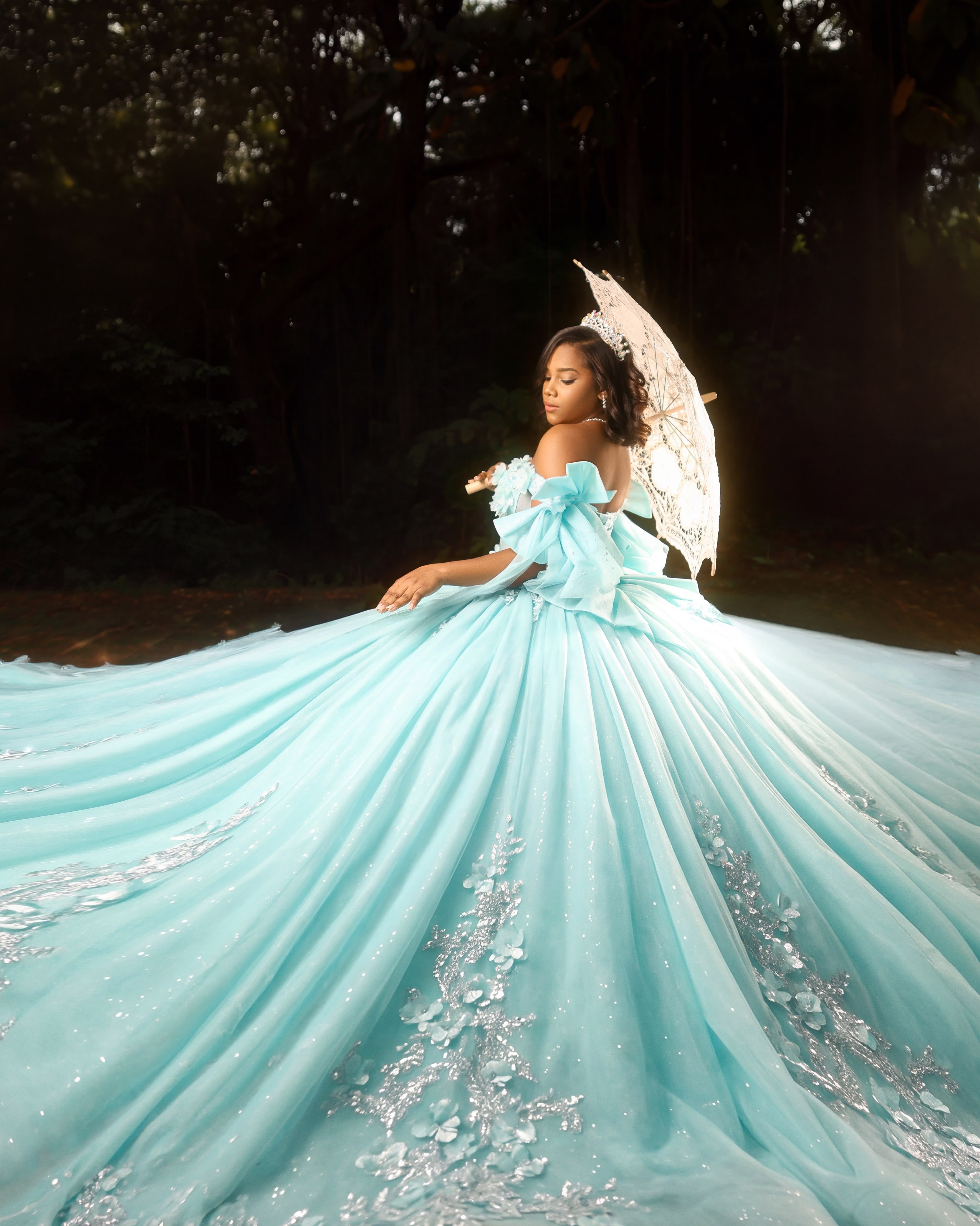 Quinceañera con vestido turquesa extendido y una sombrilla de encaje